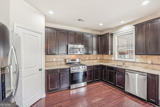 kitchen with light stone countertops, sink, dark hardwood / wood-style floors, and appliances with stainless steel finishes