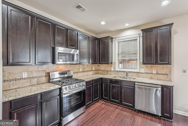 kitchen featuring sink, stainless steel appliances, dark hardwood / wood-style flooring, decorative backsplash, and dark brown cabinets