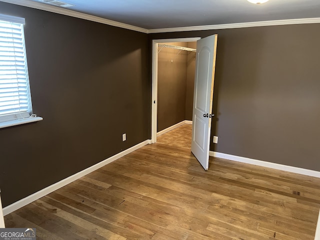 unfurnished room featuring wood-type flooring and ornamental molding