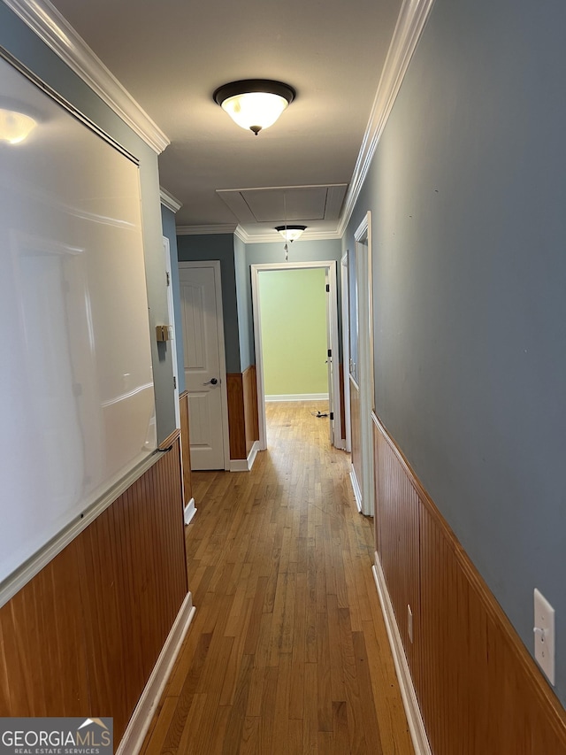 corridor with ornamental molding and light hardwood / wood-style floors