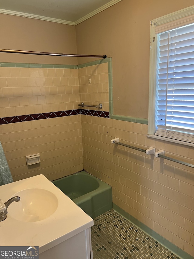 bathroom with tile walls, tile patterned flooring, ornamental molding, vanity, and  shower combination