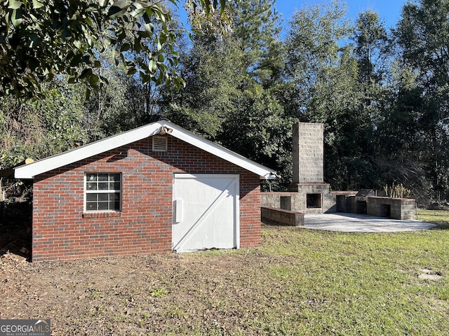 view of outdoor structure with a fireplace and a lawn