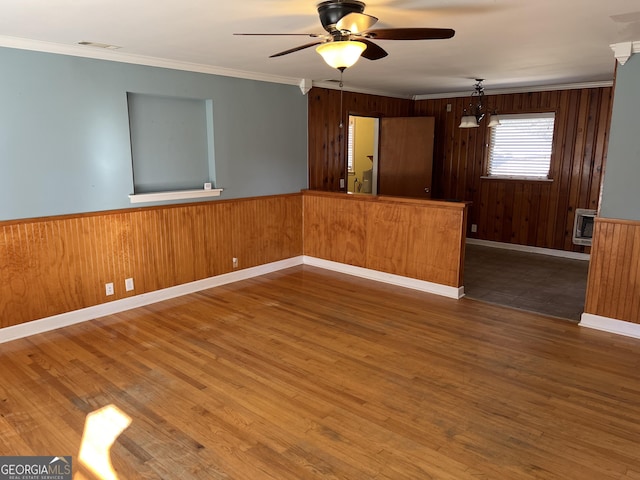 spare room featuring ornamental molding, dark hardwood / wood-style floors, and wooden walls