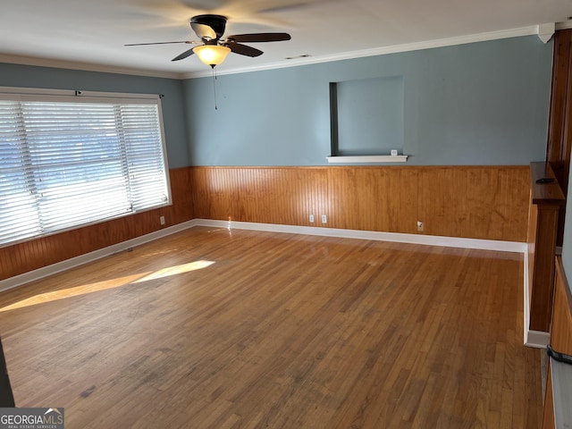 empty room with hardwood / wood-style floors, ornamental molding, and ceiling fan