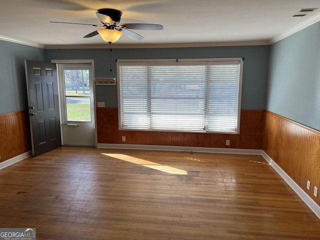 interior space featuring hardwood / wood-style floors, ornamental molding, ceiling fan, and wood walls