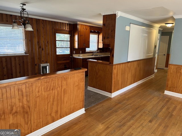 kitchen with crown molding, dark wood-type flooring, pendant lighting, and kitchen peninsula