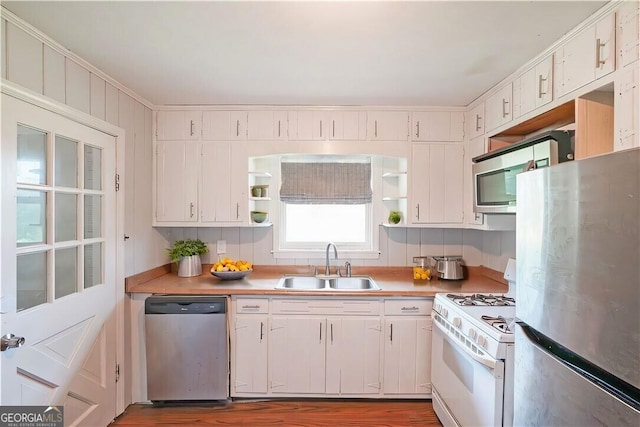 kitchen featuring appliances with stainless steel finishes, white cabinetry, crown molding, and sink