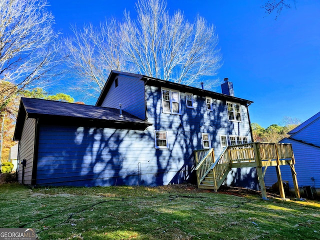 rear view of property with a wooden deck and a yard