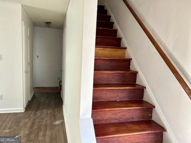 staircase with hardwood / wood-style floors and a textured ceiling