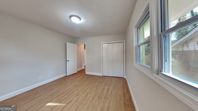 unfurnished bedroom featuring a closet, light wood-type flooring, and multiple windows