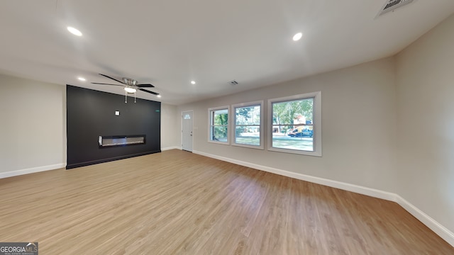 unfurnished living room featuring a fireplace, ceiling fan, and light hardwood / wood-style flooring