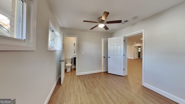 bedroom featuring light hardwood / wood-style floors, ensuite bath, multiple windows, and ceiling fan