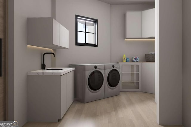 laundry area with light hardwood / wood-style floors, cabinets, sink, and washing machine and dryer