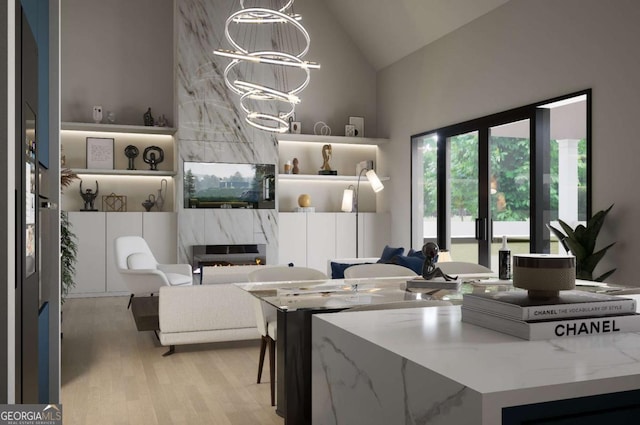 kitchen with hanging light fixtures, light wood-type flooring, light stone countertops, a fireplace, and a notable chandelier