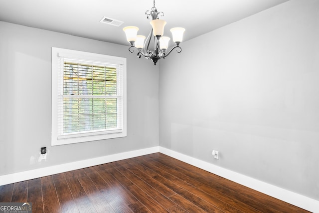empty room featuring a chandelier and dark hardwood / wood-style floors