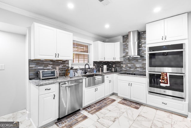 kitchen featuring wall chimney range hood, light stone counters, decorative backsplash, white cabinets, and appliances with stainless steel finishes