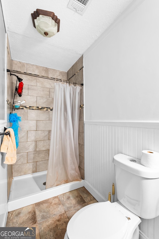 bathroom with a textured ceiling, toilet, walk in shower, and tile patterned floors