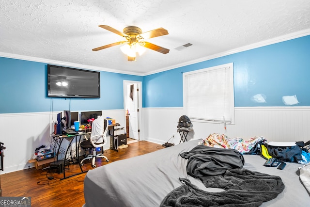 bedroom featuring hardwood / wood-style floors, ceiling fan, ornamental molding, and a textured ceiling