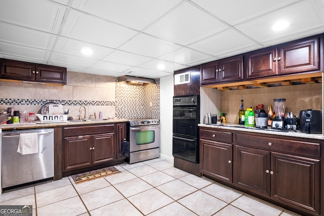 kitchen with sink, light tile patterned floors, appliances with stainless steel finishes, tasteful backsplash, and dark brown cabinetry