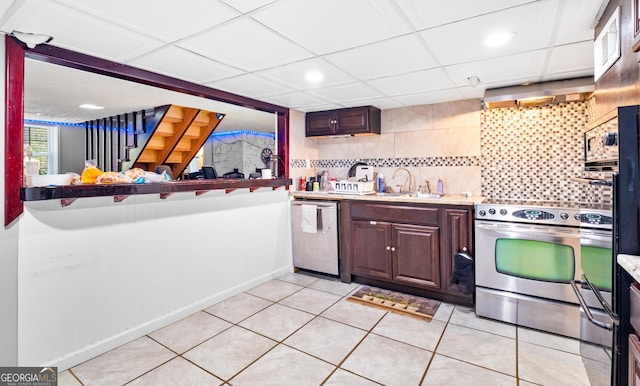 kitchen featuring sink, wall chimney exhaust hood, decorative backsplash, light tile patterned floors, and appliances with stainless steel finishes