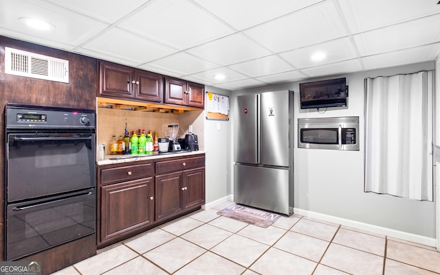 kitchen with a drop ceiling, light tile patterned floors, and appliances with stainless steel finishes