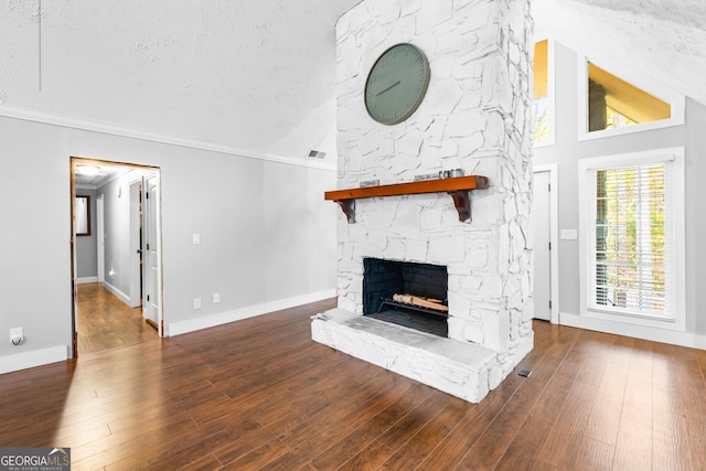 unfurnished living room with a stone fireplace, high vaulted ceiling, crown molding, hardwood / wood-style floors, and a textured ceiling