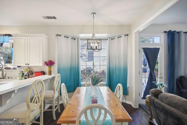 dining area featuring dark hardwood / wood-style flooring, sink, and an inviting chandelier