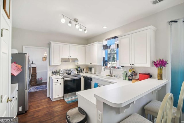 kitchen with kitchen peninsula, appliances with stainless steel finishes, a breakfast bar, white cabinets, and dark hardwood / wood-style floors