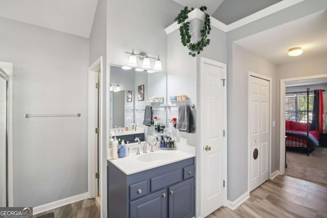 bathroom featuring hardwood / wood-style floors, vanity, and vaulted ceiling