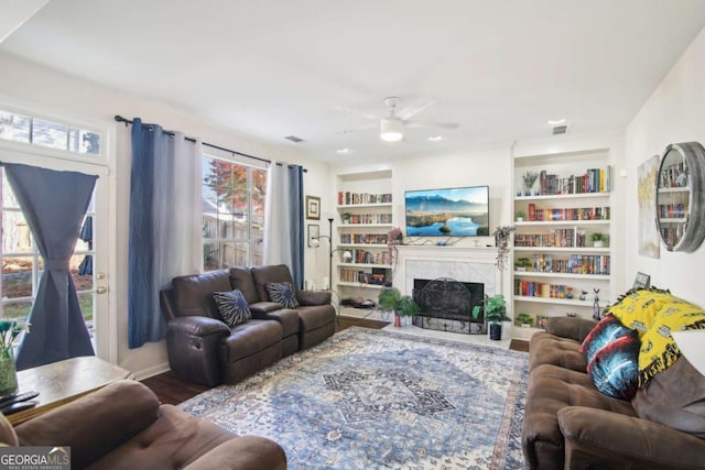 living room featuring hardwood / wood-style floors, ceiling fan, and built in shelves