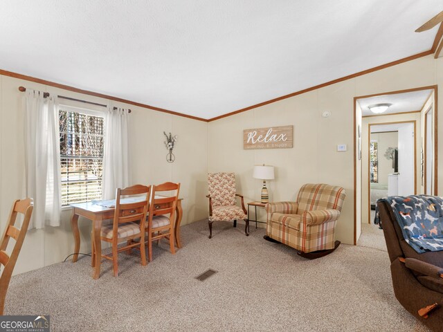 carpeted dining space with lofted ceiling and ornamental molding