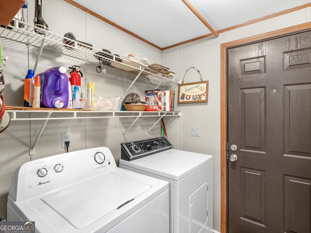 laundry area with washing machine and dryer, a textured ceiling, and ornamental molding