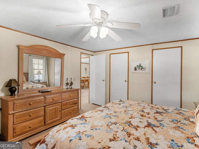 carpeted bedroom featuring ceiling fan, a textured ceiling, and ornamental molding