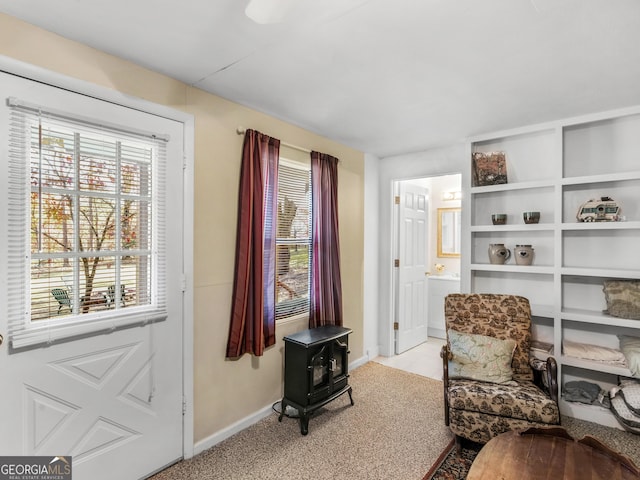 sitting room with a wood stove and light colored carpet