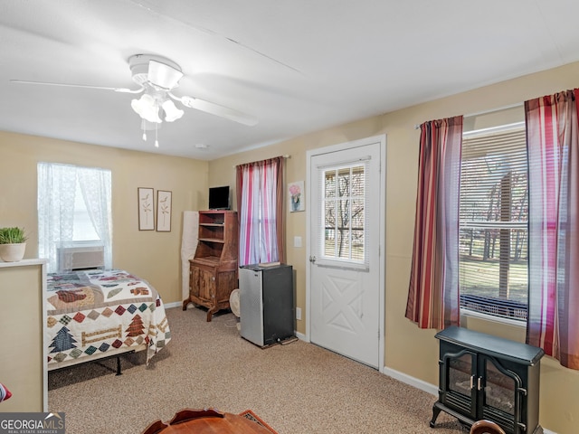 bedroom with carpet floors, a wood stove, and ceiling fan