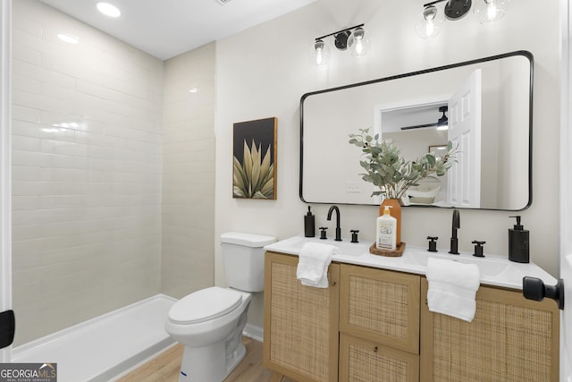 bathroom with tiled shower, wood-type flooring, vanity, and toilet