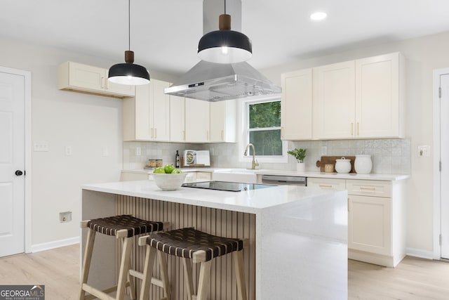 kitchen featuring white cabinetry, hanging light fixtures, light hardwood / wood-style floors, black electric stovetop, and a kitchen island