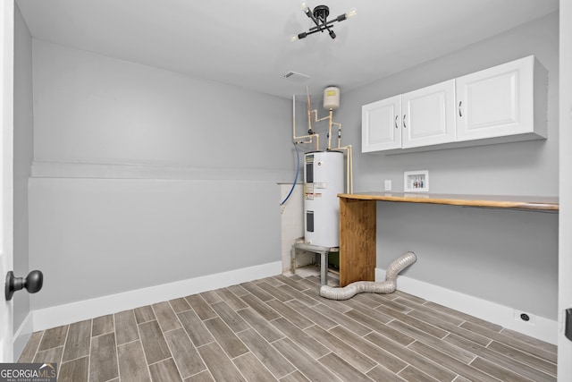 interior space with cabinets, washer hookup, electric water heater, and light hardwood / wood-style flooring