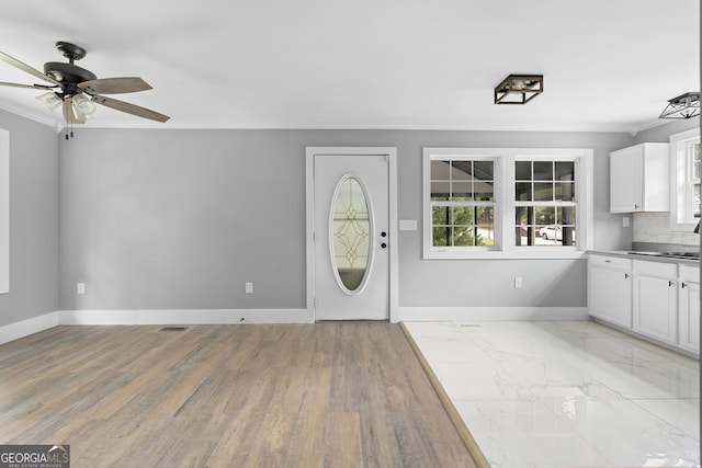 entrance foyer featuring light hardwood / wood-style flooring, ceiling fan, and ornamental molding