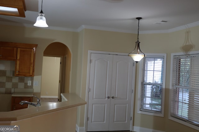 kitchen featuring backsplash, hanging light fixtures, and ornamental molding