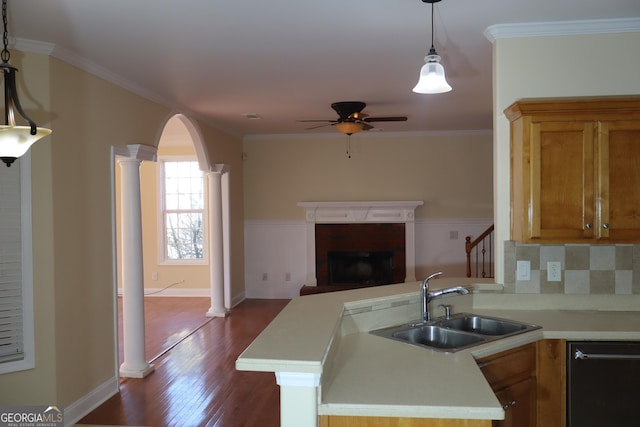 kitchen featuring kitchen peninsula, decorative columns, sink, hardwood / wood-style flooring, and black dishwasher