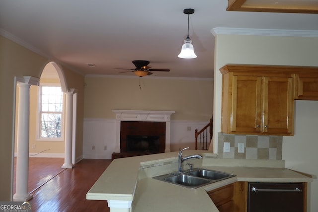 kitchen featuring kitchen peninsula, ornate columns, crown molding, sink, and hardwood / wood-style floors