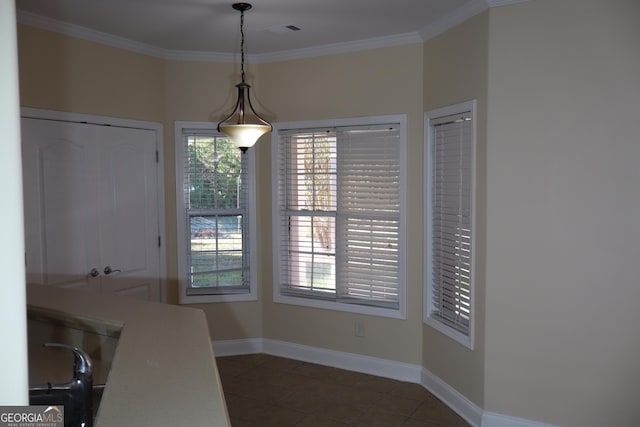 unfurnished dining area featuring a healthy amount of sunlight, ornamental molding, and dark tile patterned floors