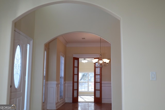 foyer with crown molding and an inviting chandelier