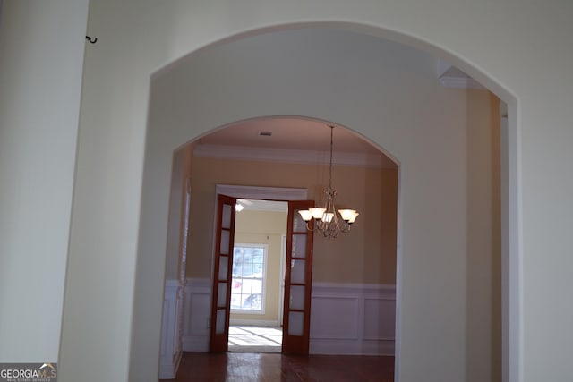 hallway with dark wood-type flooring, a chandelier, and ornamental molding