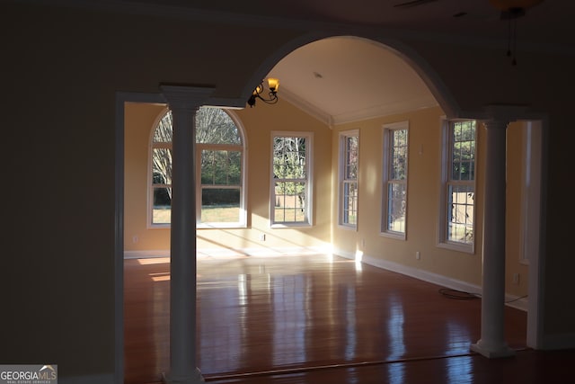 unfurnished room featuring decorative columns, vaulted ceiling, ornamental molding, wood-type flooring, and a chandelier