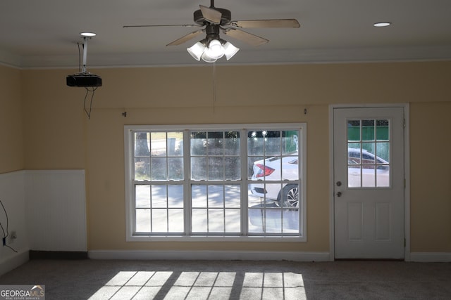 doorway to outside featuring carpet, plenty of natural light, ornamental molding, and ceiling fan