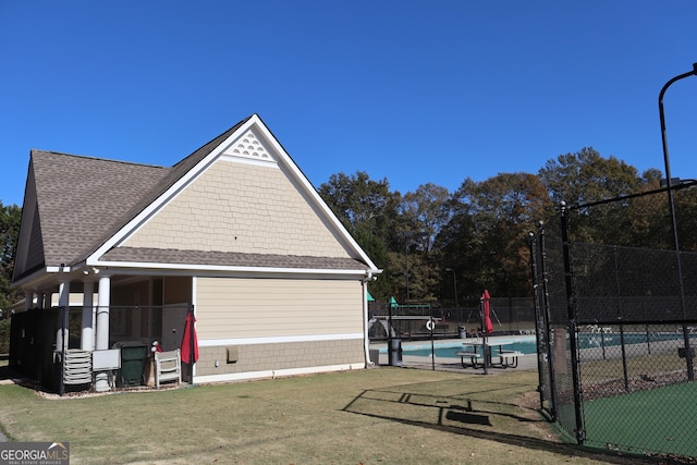 view of side of home with a fenced in pool and a lawn