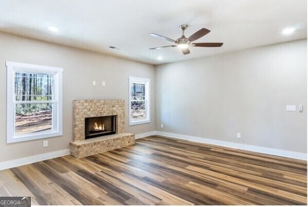 unfurnished living room with ceiling fan, plenty of natural light, and wood-type flooring