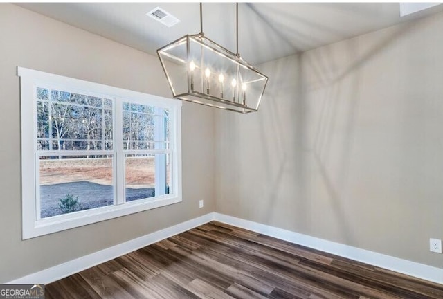 unfurnished dining area featuring dark hardwood / wood-style flooring and an inviting chandelier